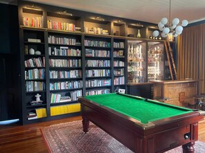 Une pièce équipée d’une table de billard, de bibliothèques et d’un coin bar.