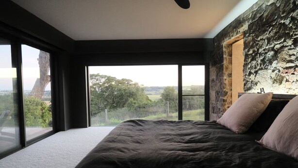 Un dormitorio con una cama grande, una pared de piedra y vistas al exterior.