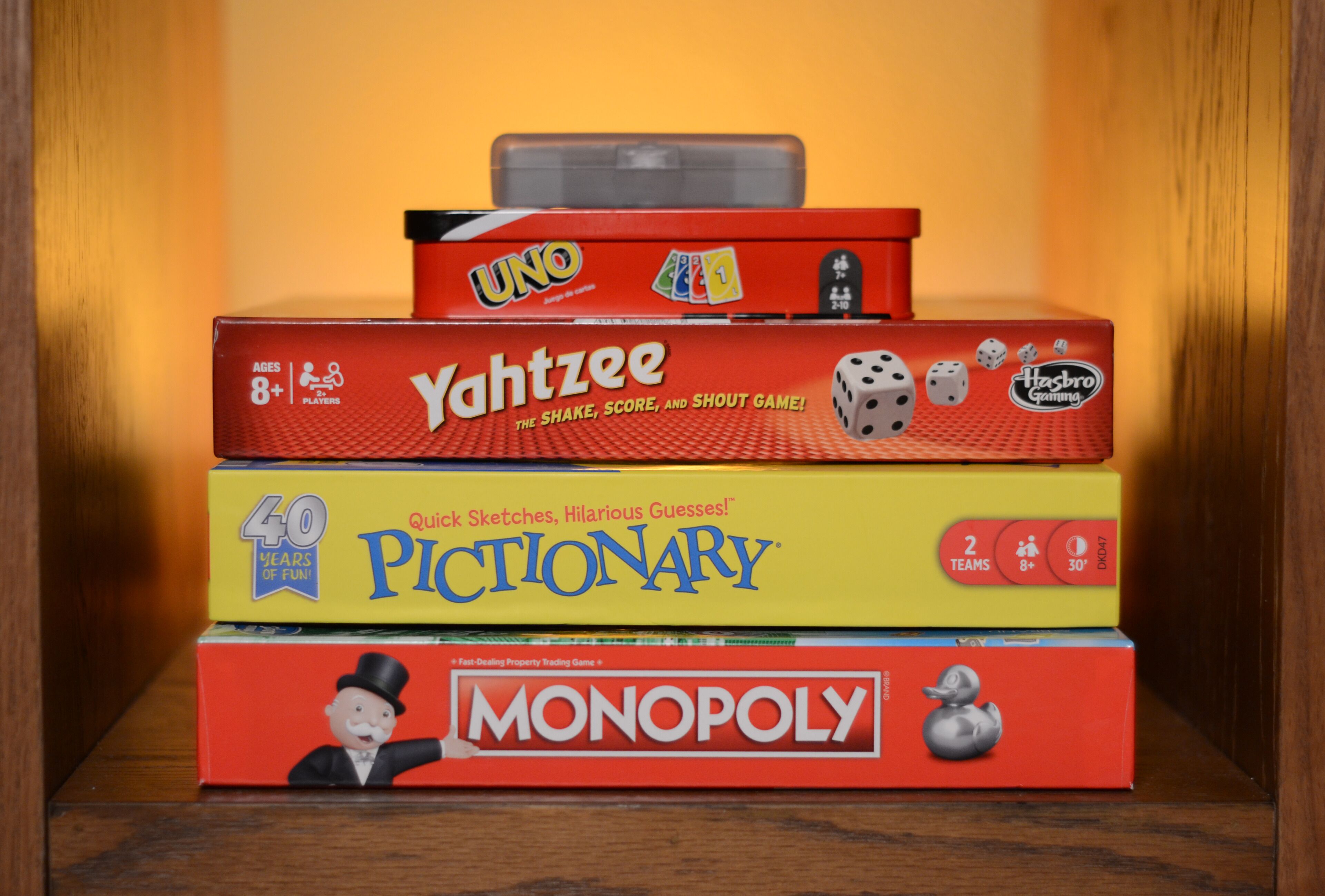 Een stapel gezelschapsspellen, waaronder UNO, Yahtzee, Pictionary en Monopoly.