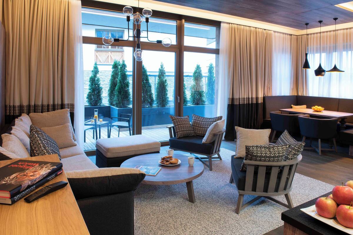 Una sala de estar moderna con un sofá, sillones, una mesa de centro y un comedor con una mesa y sillas.