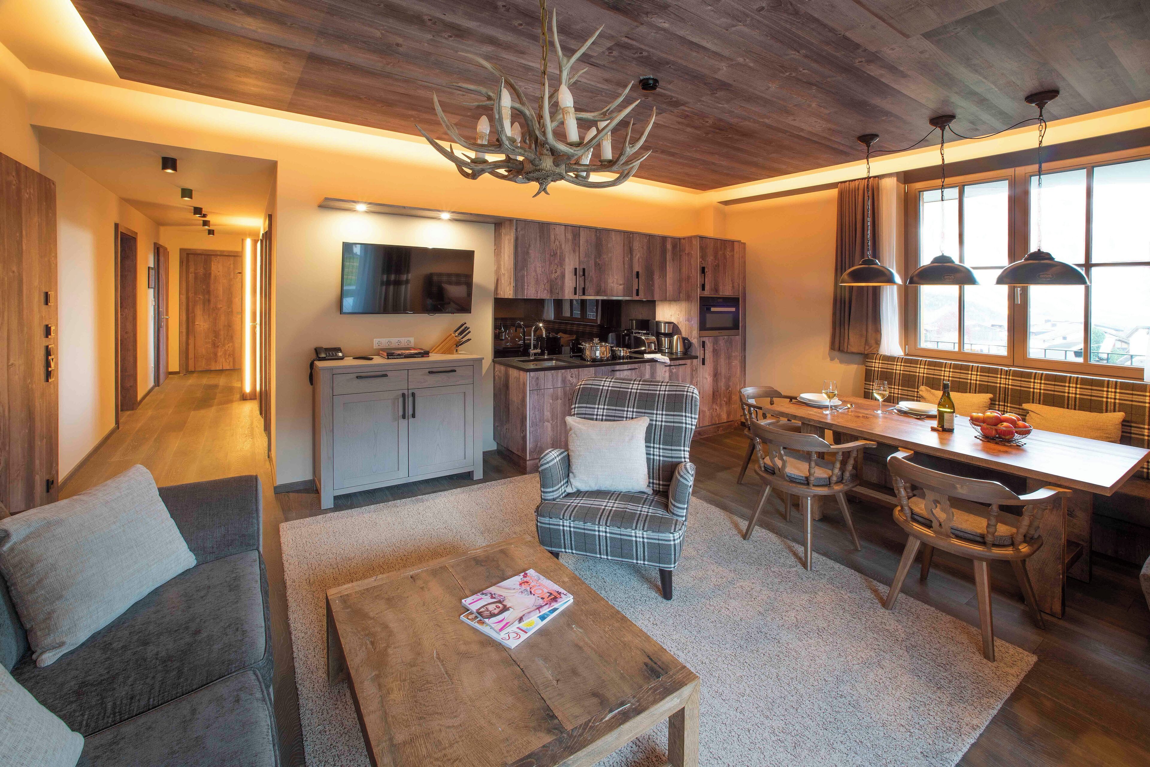 Una cocina moderna con armarios de madera, una zona de comedor con mobiliario escocés y un salón con sofá y mesa de centro.