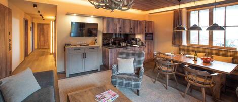 Una cocina moderna con armarios de madera, una zona de comedor con mobiliario escocés y un salón con sofá y mesa de centro.