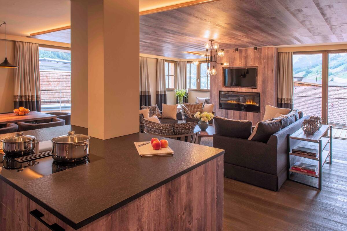 Una cocina moderna con una isla central, un comedor con sofá y una sala de estar con chimenea.