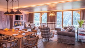 Una sala de estar moderna con chimenea, ventanas amplias y un comedor con muebles de madera.