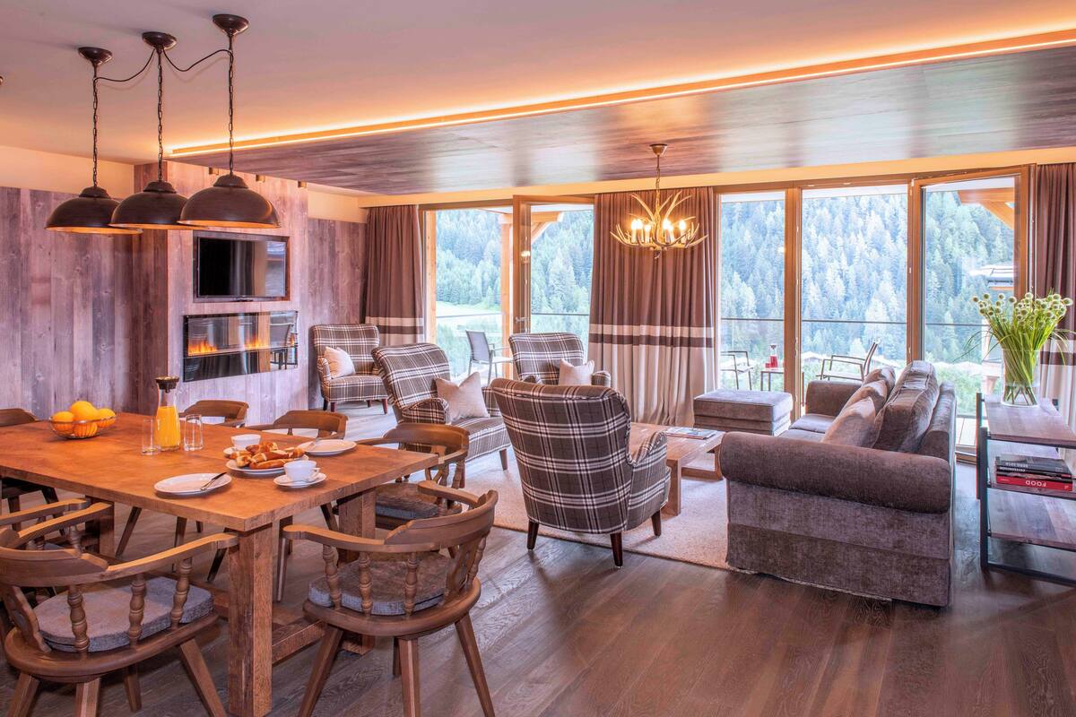 Una sala de estar moderna con chimenea, ventanas amplias y un comedor con muebles de madera.