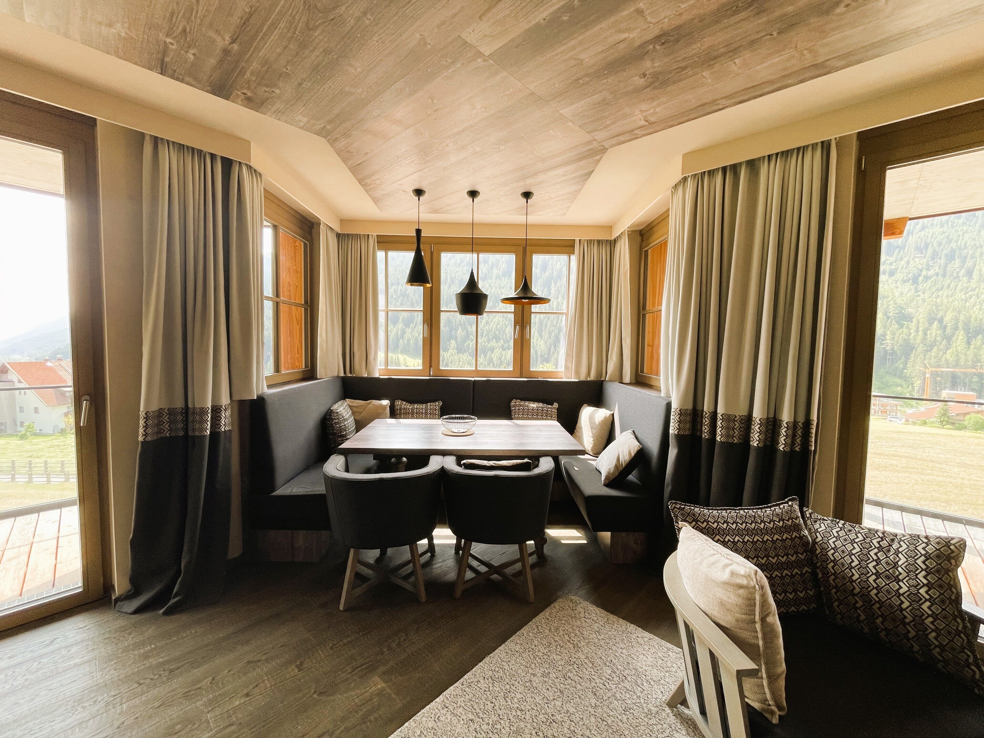 A cozy dining area with a wooden table, black chairs, and a bench. There are two pendant lights hanging above the table.