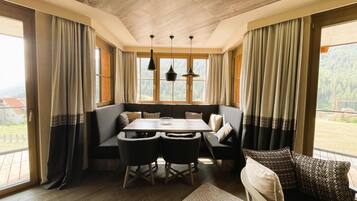 A cozy dining area with a wooden table, black chairs, and a bench. There are two pendant lights hanging above the table.