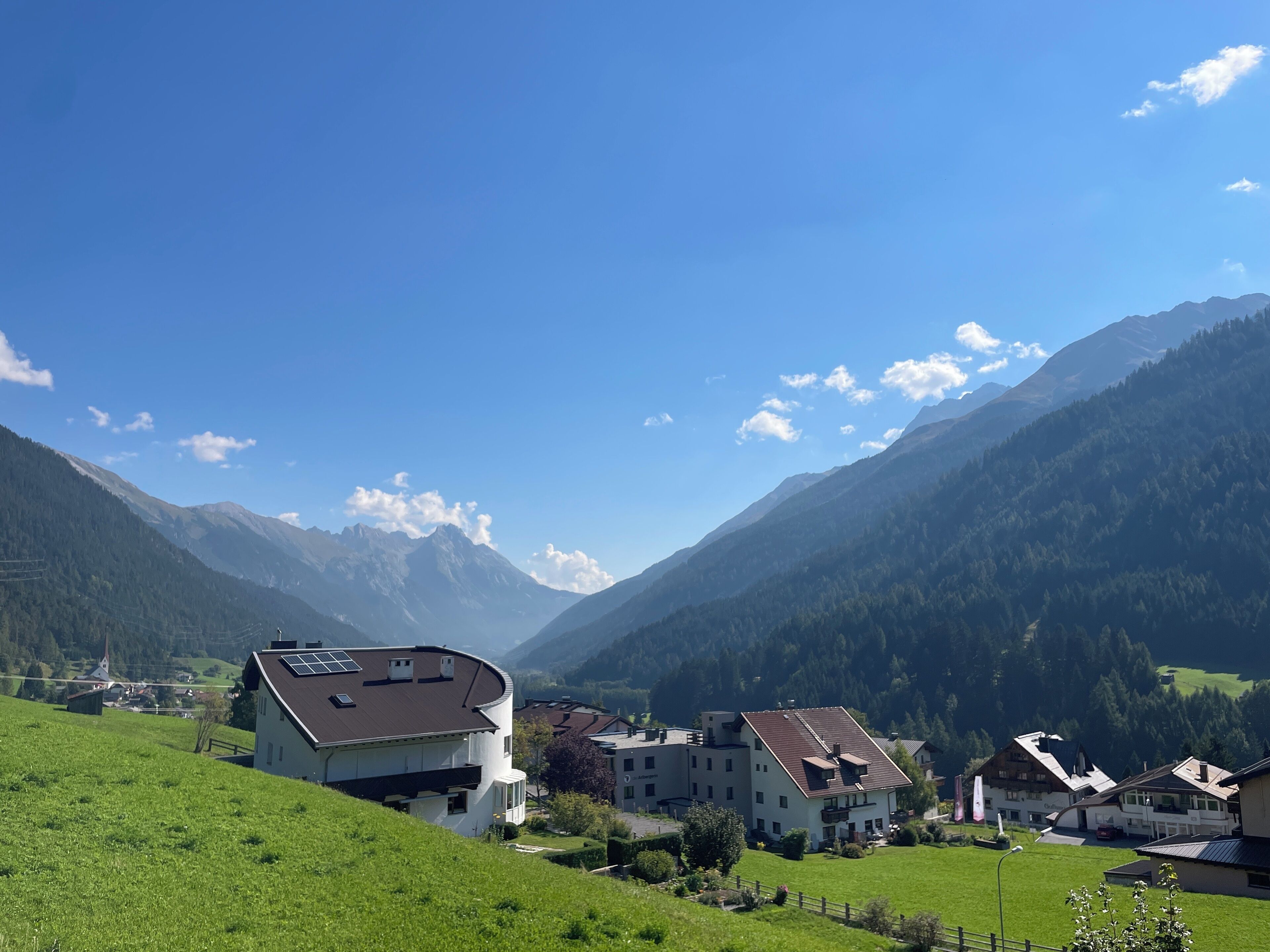A mountain village with traditional houses, a church, and a clear blue sky.