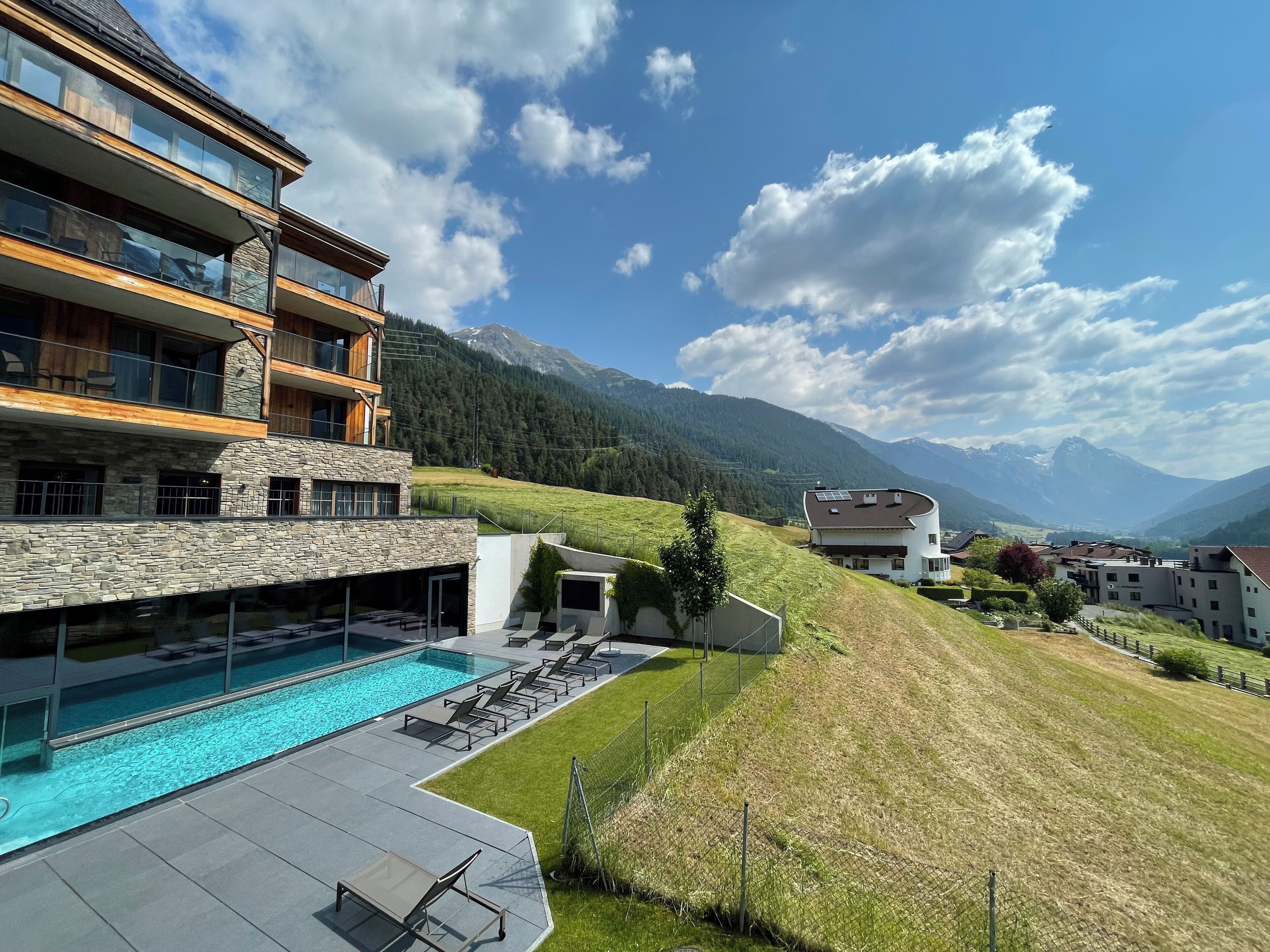 Un hôtel moderne doté d’une piscine, d’une façade en pierre et offrant une vue sur les montagnes.