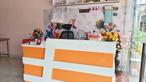A reception area with a white counter, red chairs, a calendar, and decorative flowers.