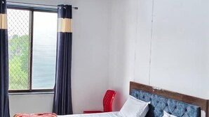 A bedroom with a bed, a red chair, a ceiling fan, and a window with curtains.