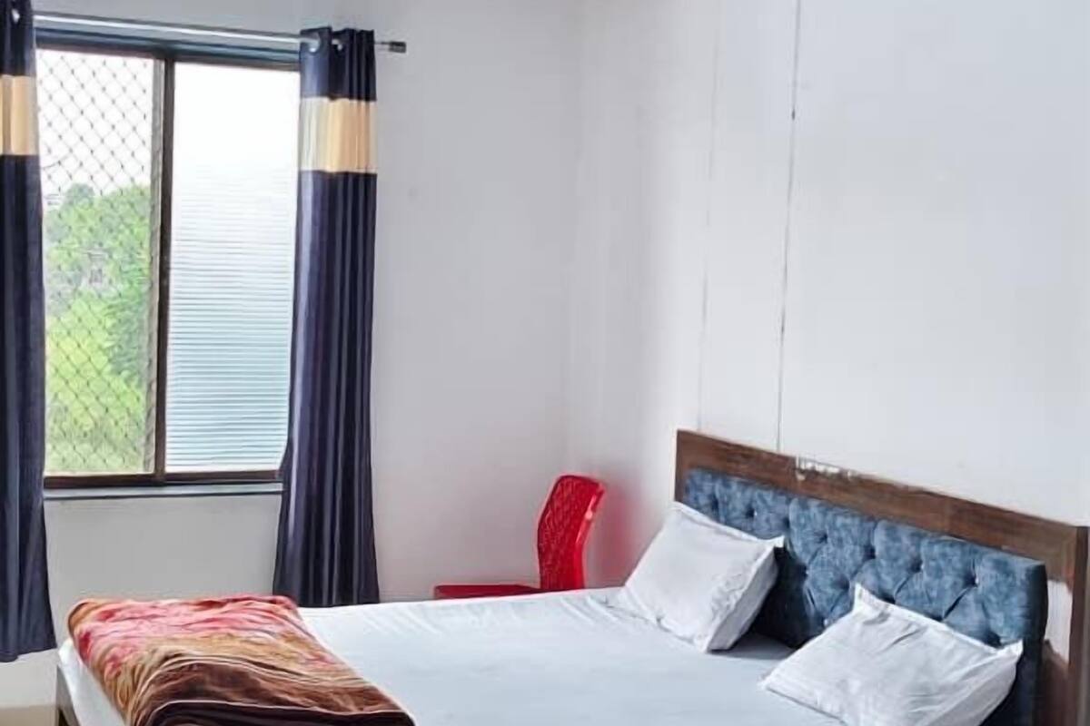 A bedroom with a bed, a red chair, a ceiling fan, and a window with curtains.