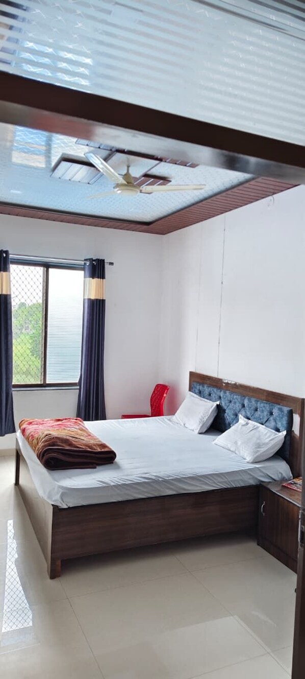 A bedroom with a bed, a red chair, a ceiling fan, and a window with curtains.