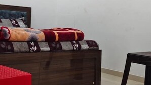 A bedroom with a bed, a red chair, a ceiling fan, and an air conditioning unit.