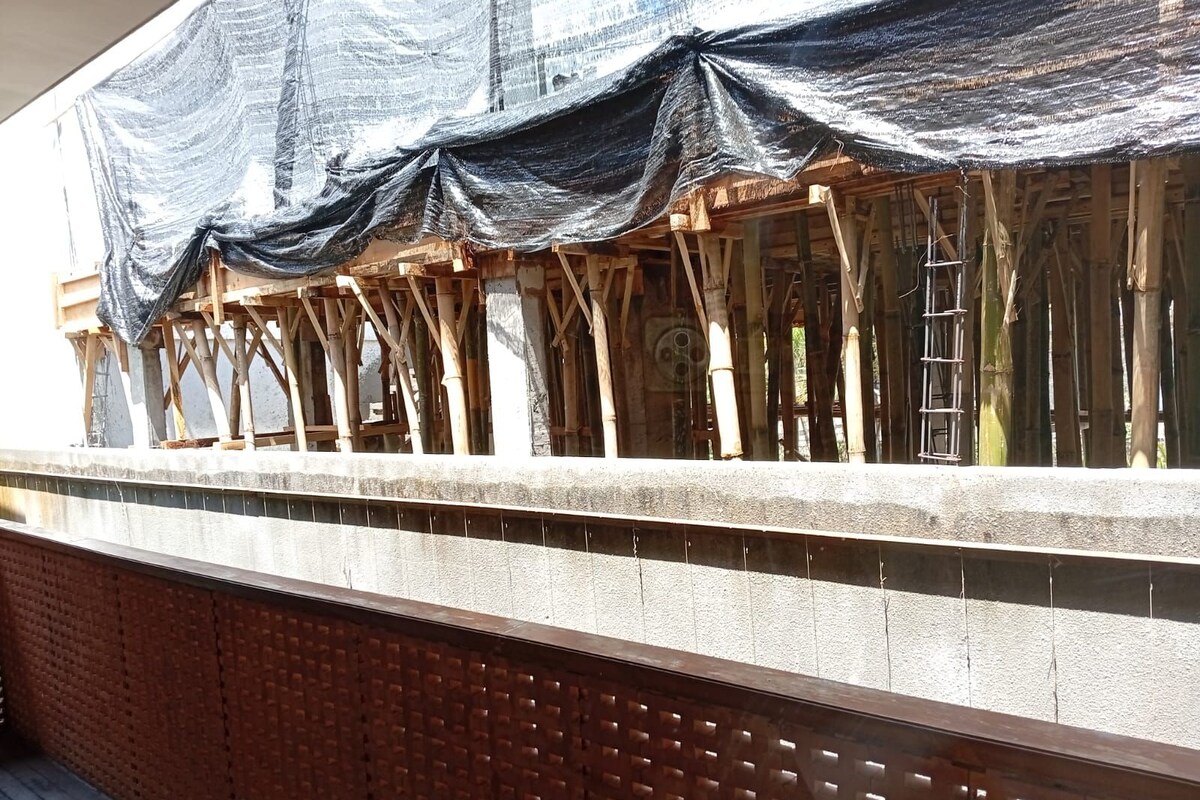 A construction site with exposed wooden beams and a partially covered area with a black tarp.