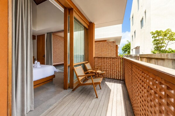 A balcony with a bed, wooden chairs, and a wooden lattice partition. - Jaladhi Echo Beach Villa (Canggu)
