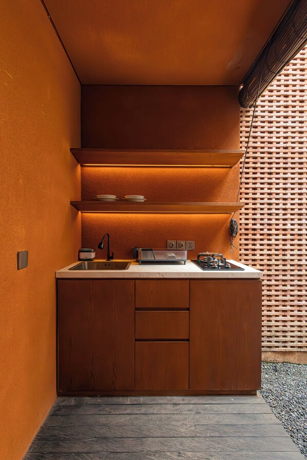 A modern kitchen with a built-in island, stainless steel appliances, and a wooden cabinet. - Jaladhi Echo Beach Villa (Canggu)