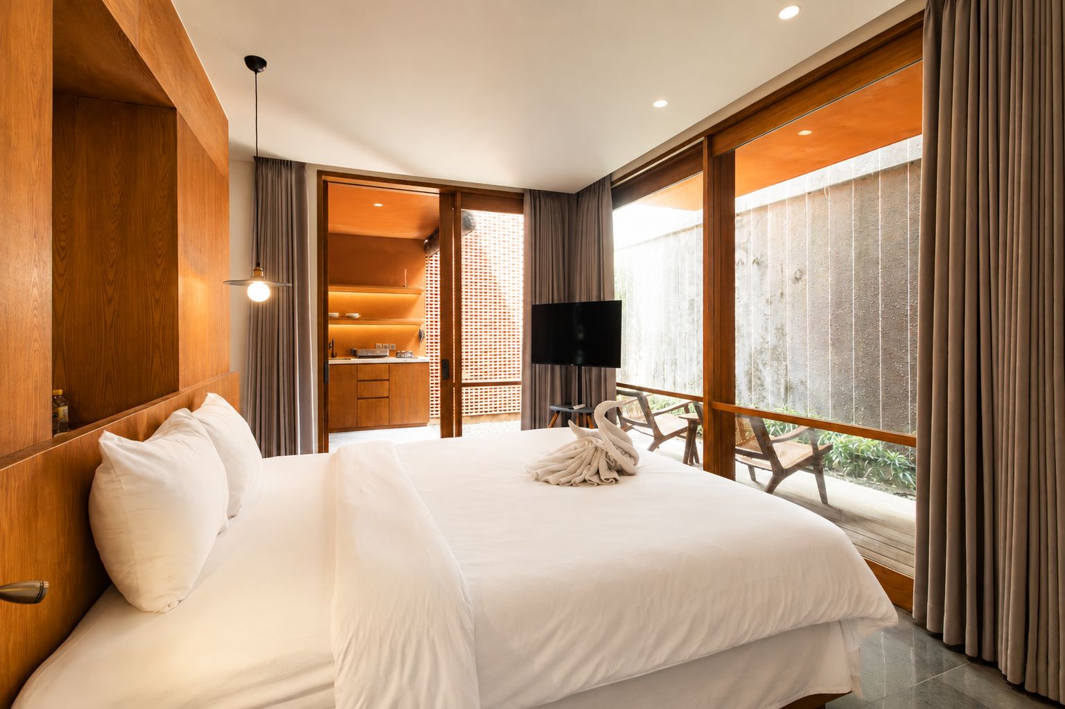 A modern hotel room with a large bed, a TV, and a balcony with a view.