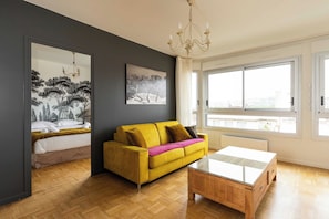 Een moderne woonkamer met een bank, een bijzettafeltje en een groot raam.
