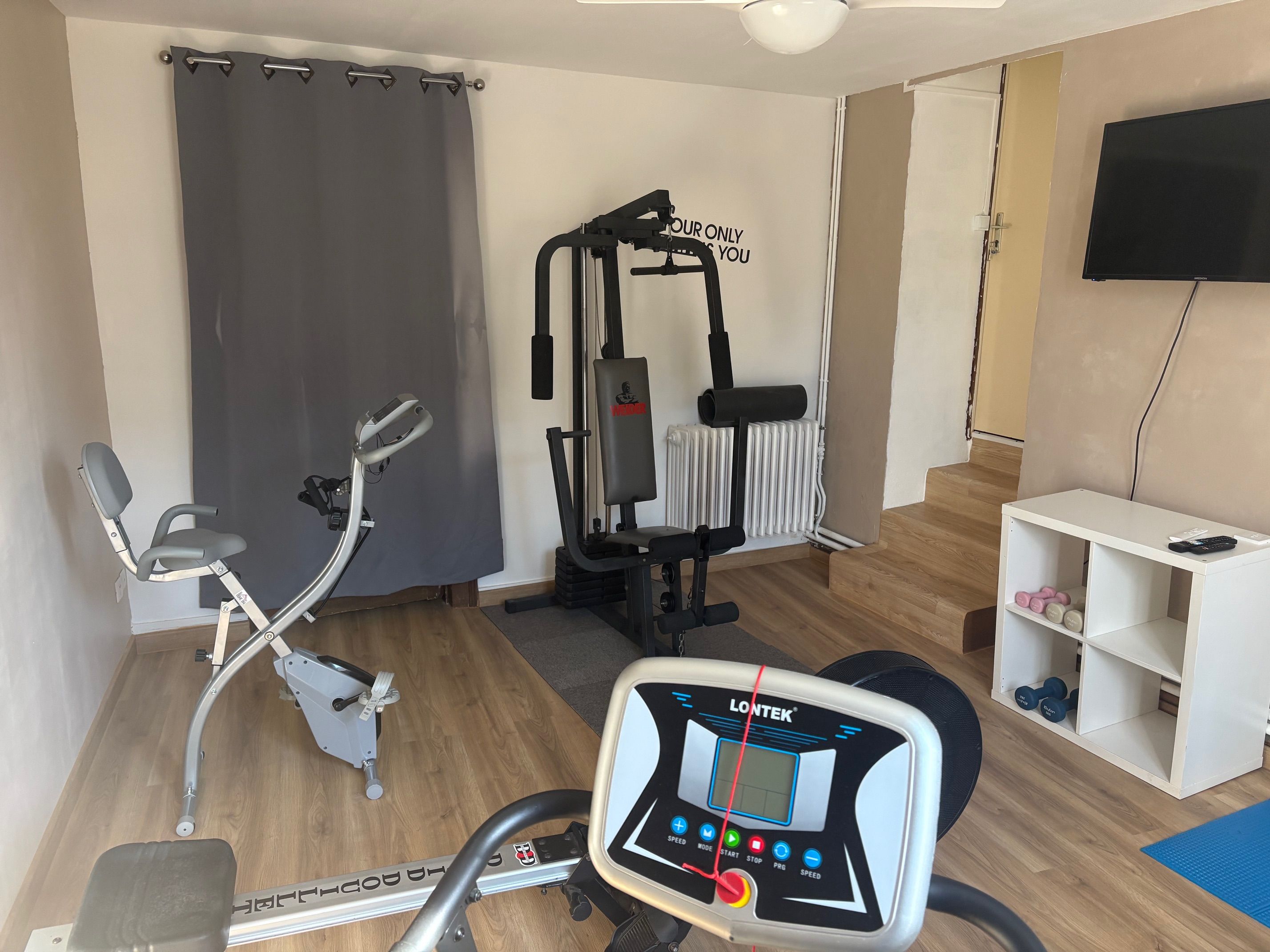 A home gym with a stationary bike, a weight machine, and a treadmill.