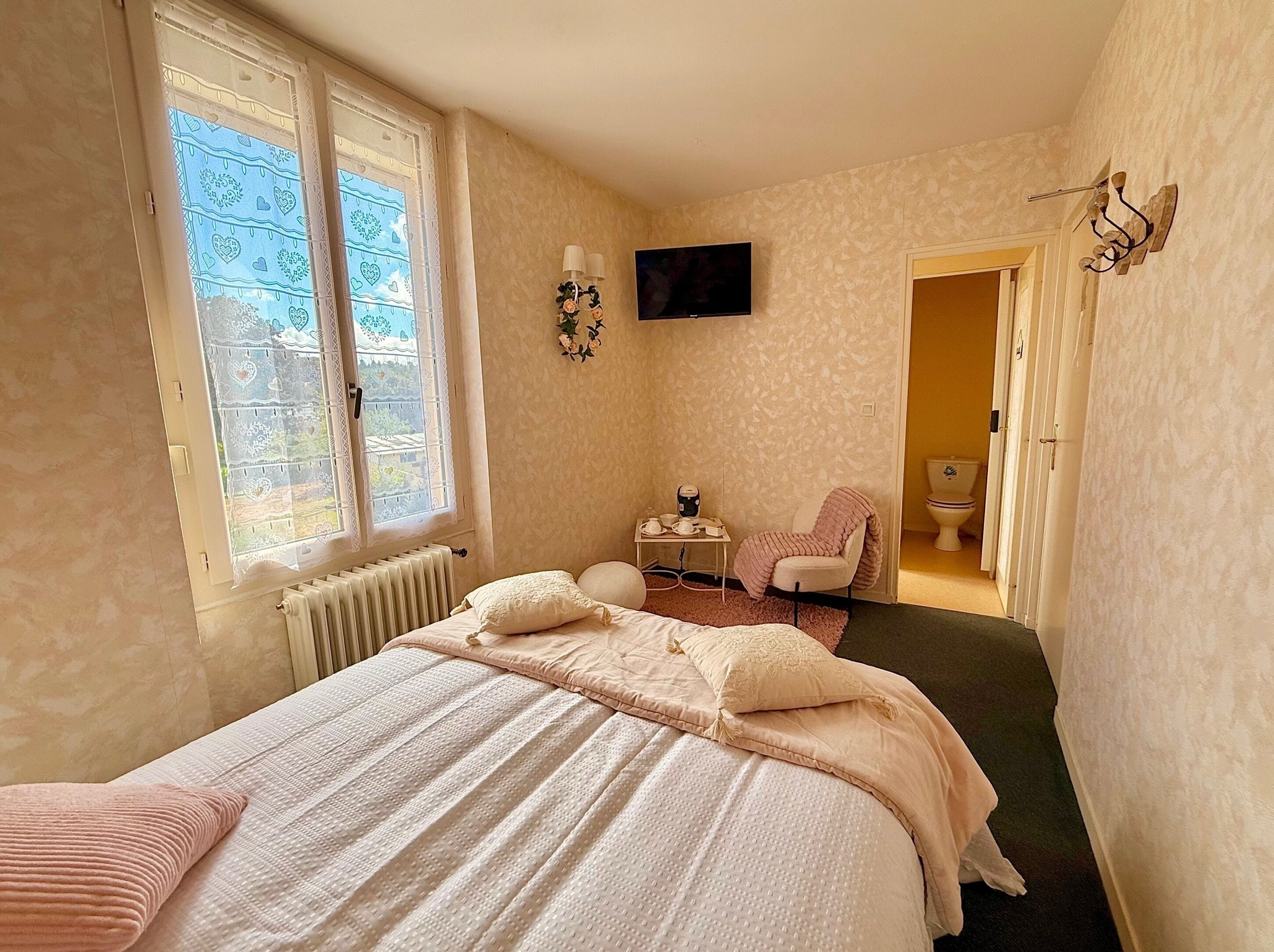 Un dormitorio con una cama, televisión, una silla y una mesita.