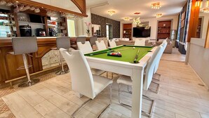 A pool table in a modern living room with a bar area and seating. - L'Orée des Rêves et des Mets (Vibraye)