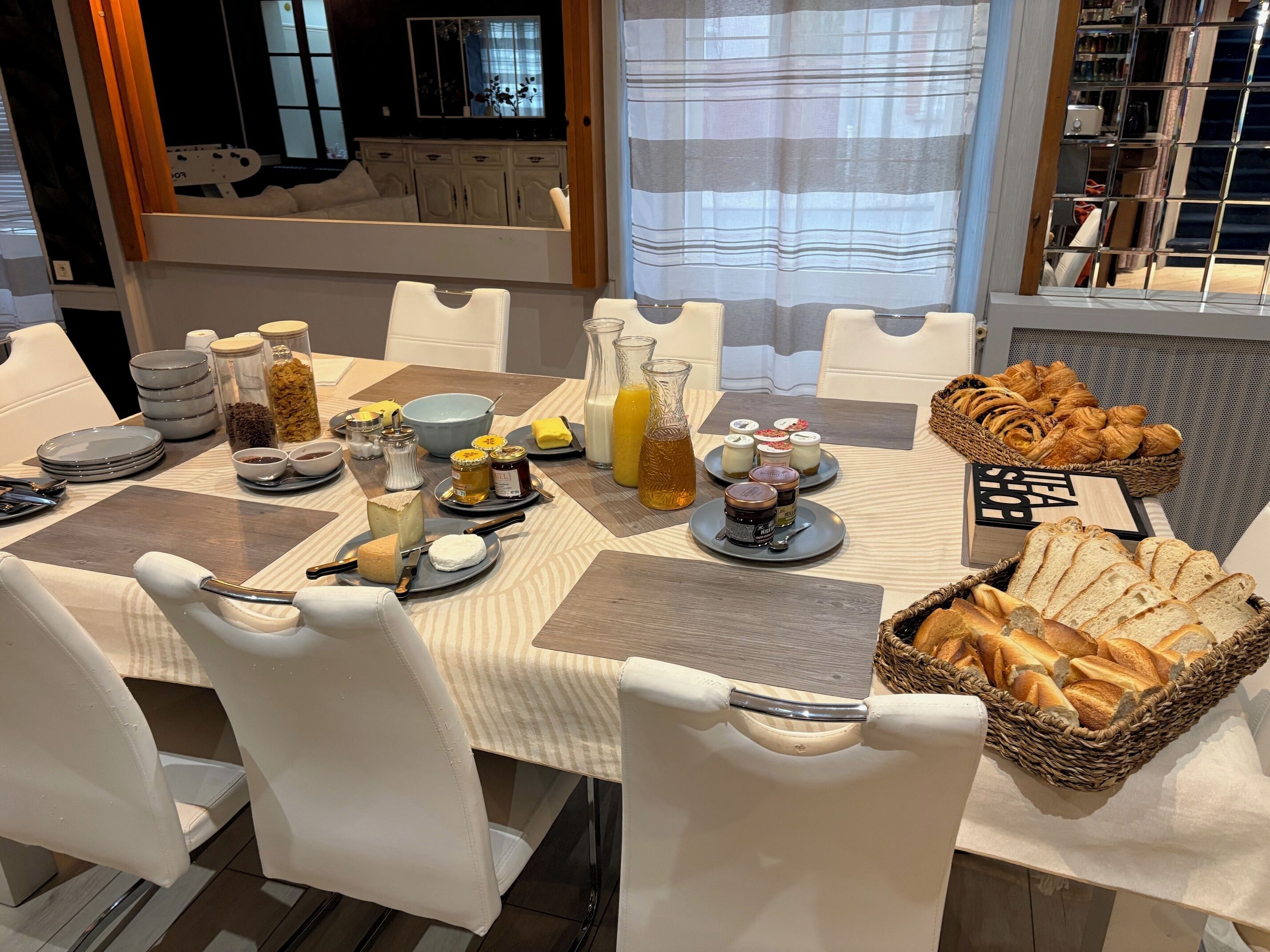 Ein reichhaltiges Frühstücksbuffet mit verschiedenen Speisen und Beilagen auf einem Tisch, umgeben von weißen Stühlen.
