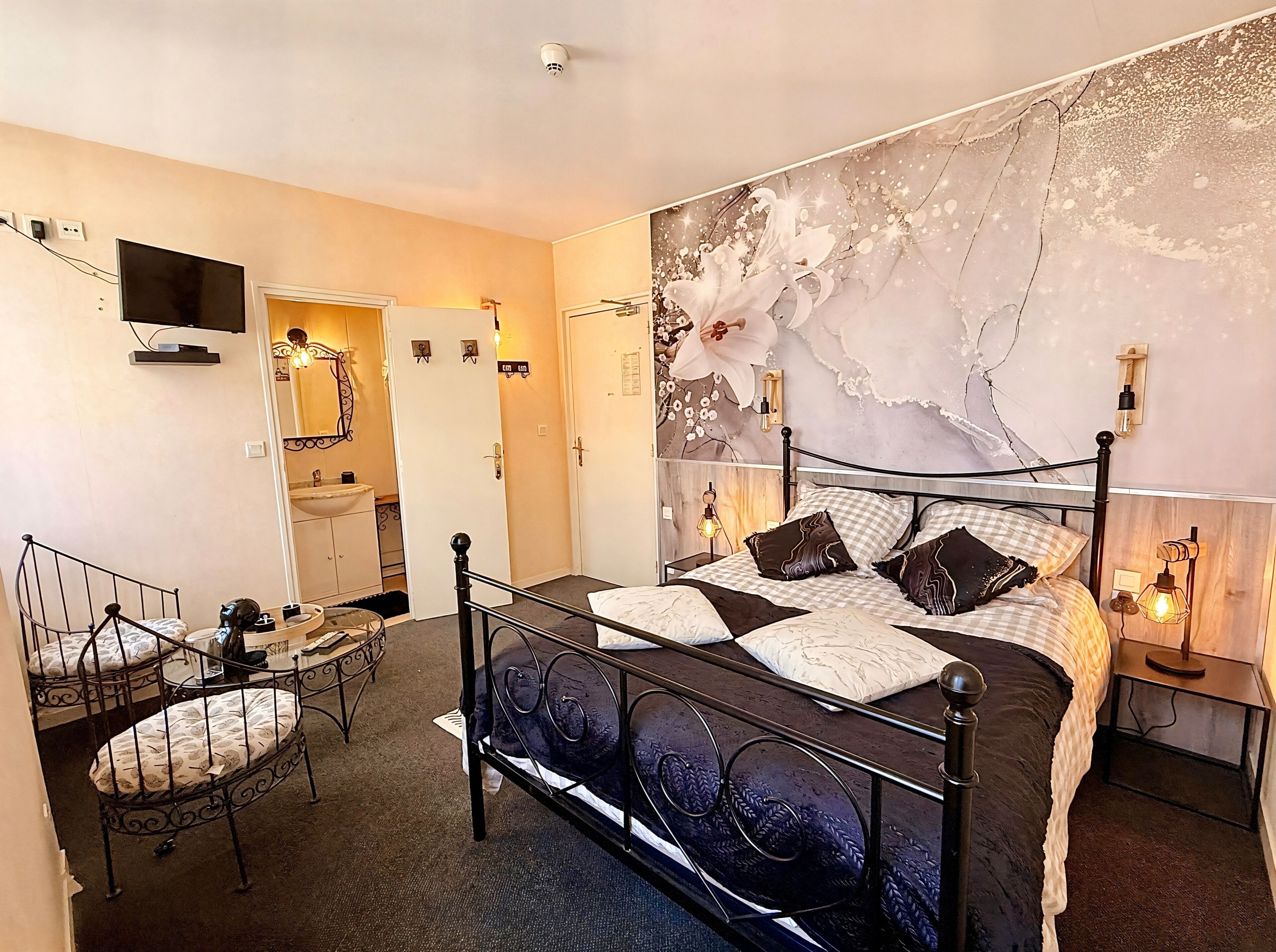 Een slaapkamer met een bed, een bureau, een stoel, een spiegel en een tv aan de muur.
