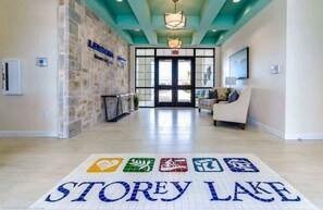 Een hotel lobby met een receptiebalie, een zithoek en een bord met daarop 'STOREY LAKE'.
