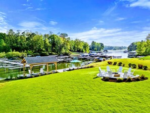 A lakeside property with a grassy lawn, a gazebo, and docked boats.