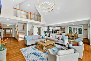 Ein großzügiger Wohnbereich mit Couchtisch, Sofas, einer Treppe und einer Küche im Hintergrund.