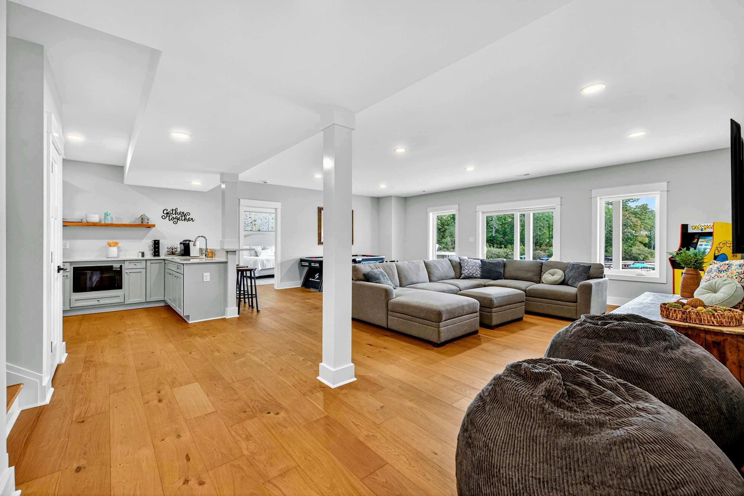 A spacious living area with a large sectional sofa, a kitchen with light grey cabinets, and a dining area with a table and chairs.