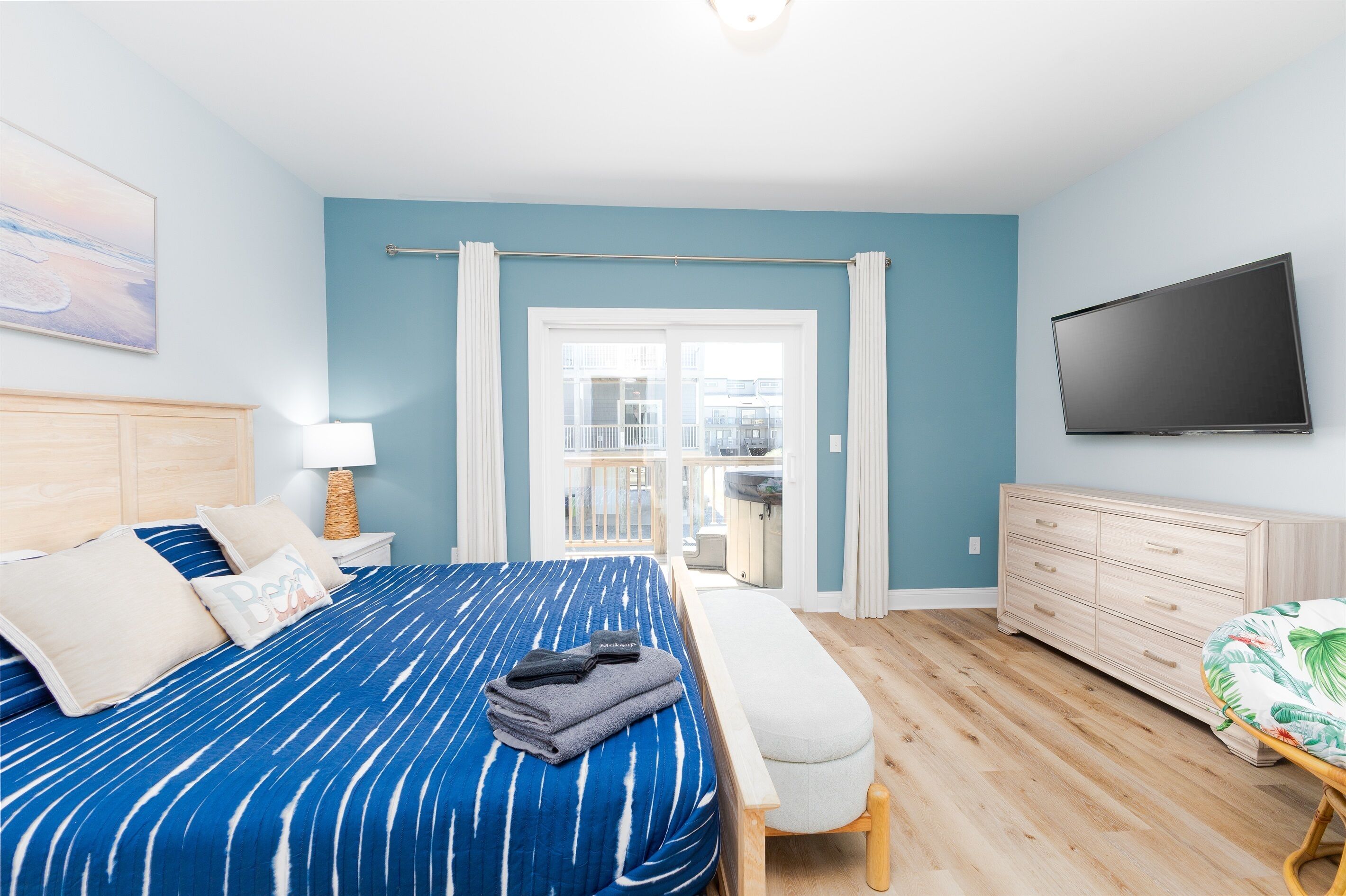 Une chambre à coucher avec un lit, une télévision, une commode et un balcon.
