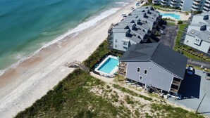 Eine Luftaufnahme einer Strandimmobilie mit mehreren Gebäuden, einem Swimmingpool und einem Strand.