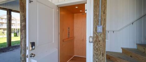 An open door to a room with a wooden floor and a light fixture.