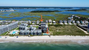 Luftaufnahme eines Küstenresorts mit mehreren Gebäuden, einem Strand und einer Marina.