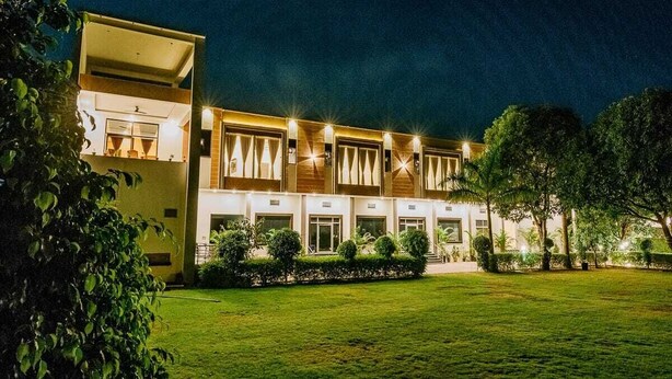 A modern hotel with a two-story structure, a well-maintained lawn, and a series of windows with curtains. - Aditya Palace (Pushkar)