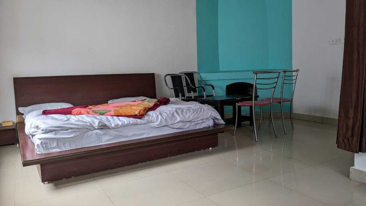 A bedroom with a bed, a desk, and two chairs.