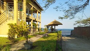 Un hotel con una estructura de varios pisos, una zona de estar cubierta al aire libre y vistas al mar.