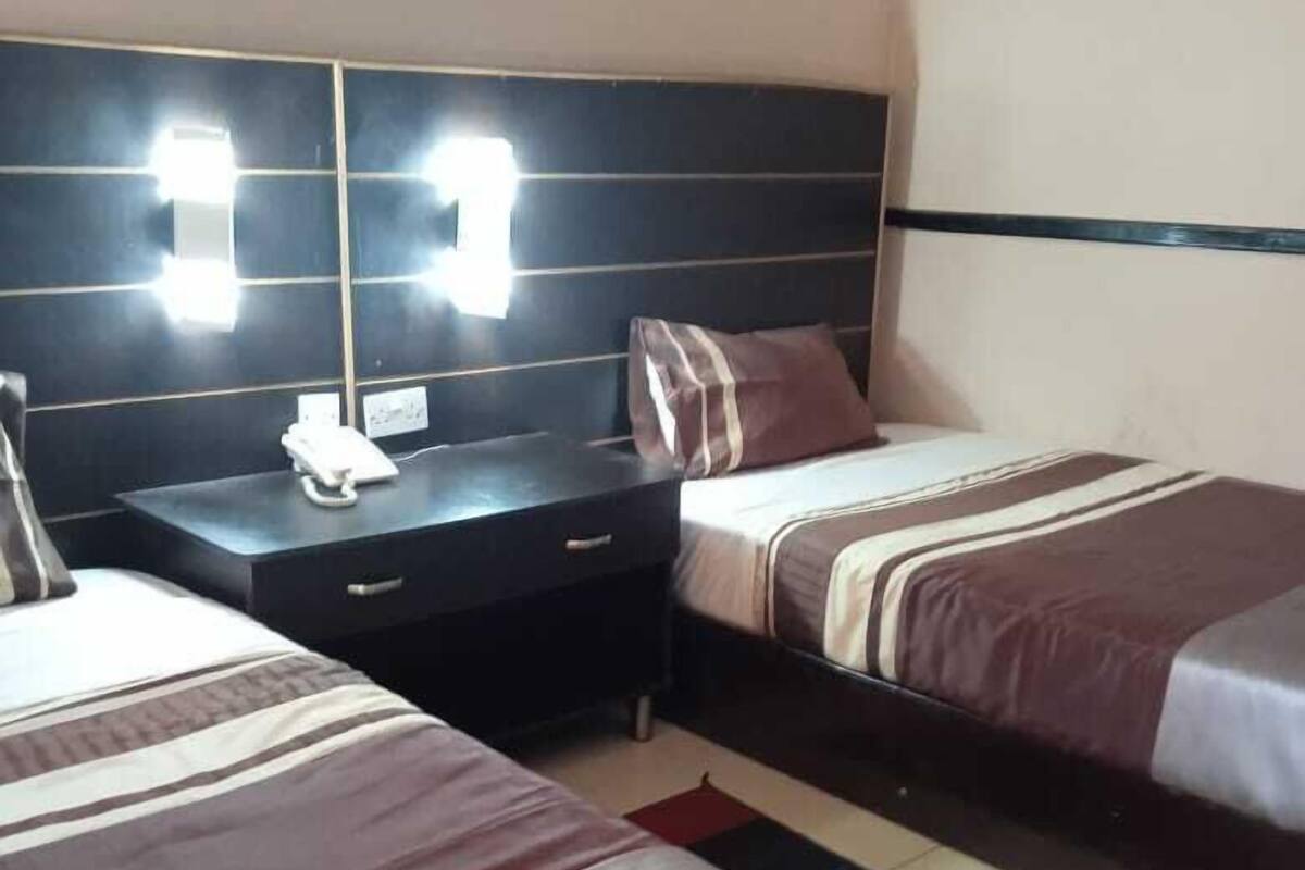 A hotel room with two beds, a desk, and a telephone.