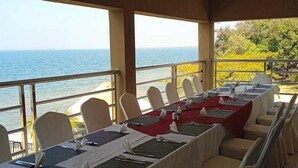 Una larga mesa de comedor dispuesta para una comida, con sillas, con vistas a un cuerpo de agua.
