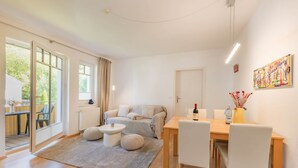 A modern living room with a sofa, a dining table with chairs, a coffee table, and a painting on the wall.