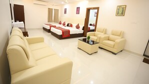 A modern hotel room with a large bed, two sofas, a coffee table, and a mirror. - Aswin Residency (Namakkal)