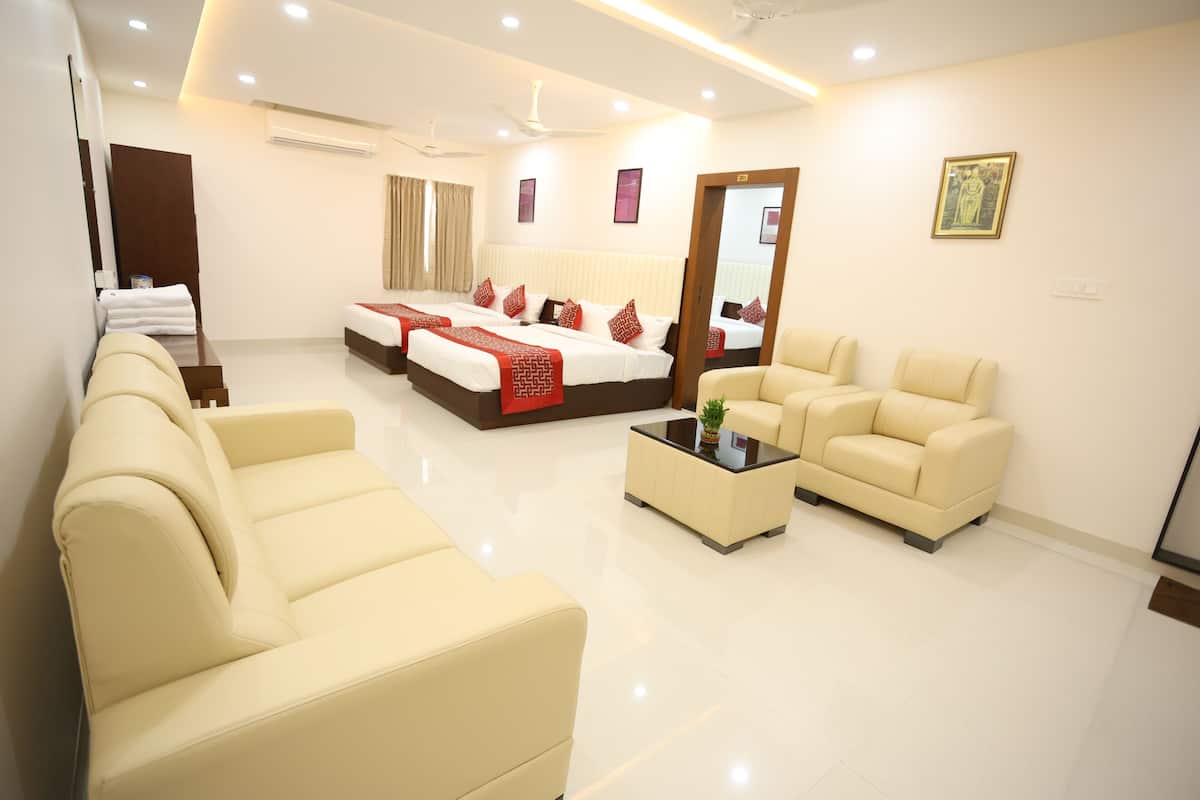 A modern hotel room with a large bed, two sofas, a coffee table, and a mirror.