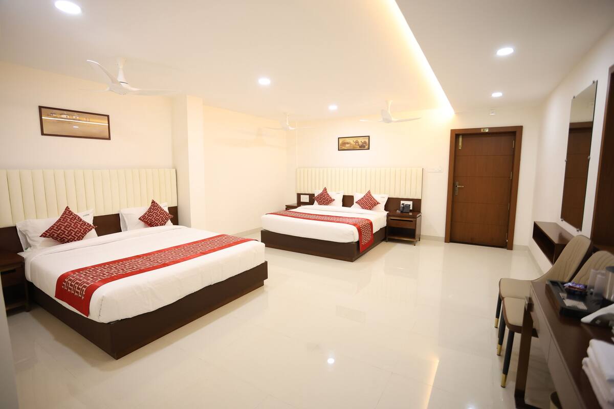 A hotel room with two beds, a desk, a chair, a wardrobe, and a door.