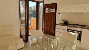 A modern kitchen with a gas stove, a coffee maker, and a view of a building through the open door. - Mediterranean: Pool and Parking on site, in the Center of Taormina (Taormina)