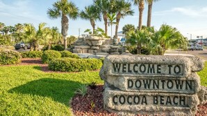 Willkommensschild für Downtown Cocoa Beach mit Palmen und blauem Himmel.