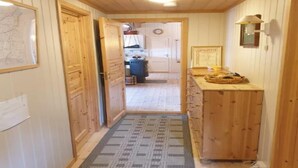 Un pasillo de madera con una alfombra que lleva a una habitación con mostrador de madera y una cesta.