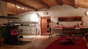 Una cocina acogedora con vigas de madera, una zona de comedor con mantel rojo y un cuadro en la pared.