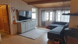 Una sala de estar acogedora con televisor, sofá, chimenea y techo de madera.